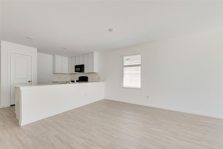 Kitchen with white cabinetry, range, kitchen peninsula, and light wood-type flooring