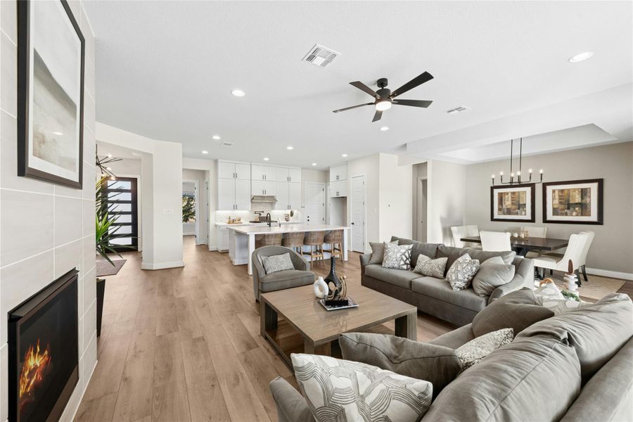 Living room with a tile fireplace, ceiling fan, light wood finished floors, recessed lighting, and a chandelier Living room with a tile fireplace, ceiling fan, light wood finished floors, recessed lighting, and a chandelier