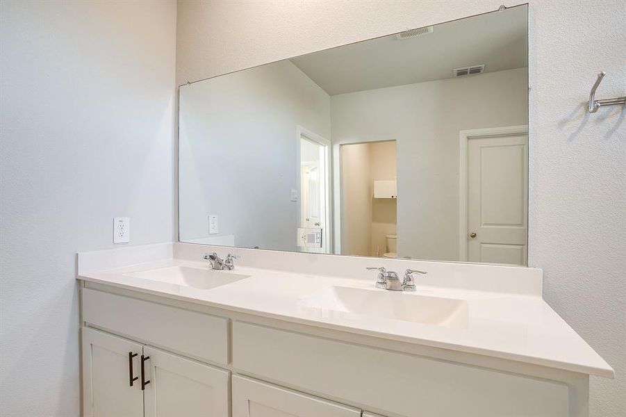 Full bathroom with double vanity and a textured wall