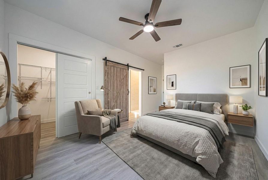 Bedroom with a closet, wood finished floors, a barn door, and a ceiling fan