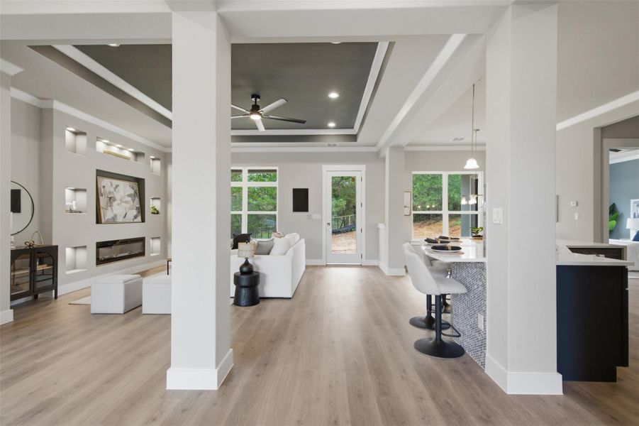 An open floorplan seamlessly connects the living area, featuring a modern fireplace, with a kitchen island and plentiful windows. An open floorplan seamlessly connects the living area, featuring a modern fireplace, with a kitchen island and plentiful windows.