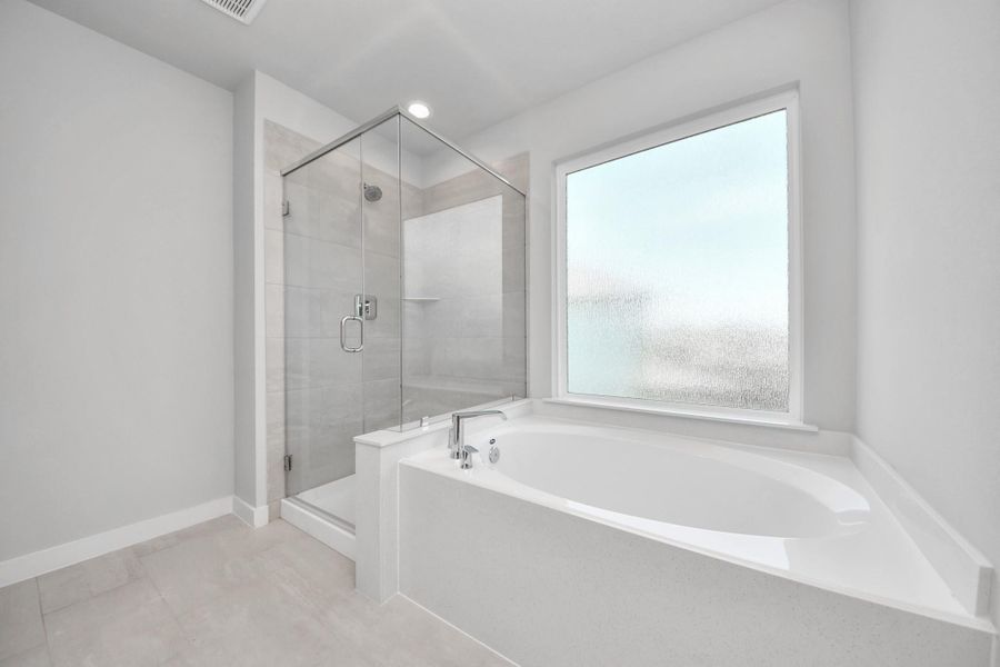 Escape to a spa-like oasis in this primary bathroom. Enjoy a walk-in shower with tile surround, a separate garden tub with custom detailing, and an elegant vanity featuring light countertops, modern hardware, and beautiful recessed lights. Experience luxury and relaxation in every detail. Sample photo of completed home with similar floor plan. Actual colors and selections may vary. Escape to a spa-like oasis in this primary bathroom. Enjoy a walk-in shower with tile surround, a separate garden tub with custom detailing, and an elegant vanity featuring light countertops, modern hardware, and beautiful recessed lights. Experience luxury and relaxation in every detail. Sample photo of completed home with similar floor plan. Actual colors and selections may vary.