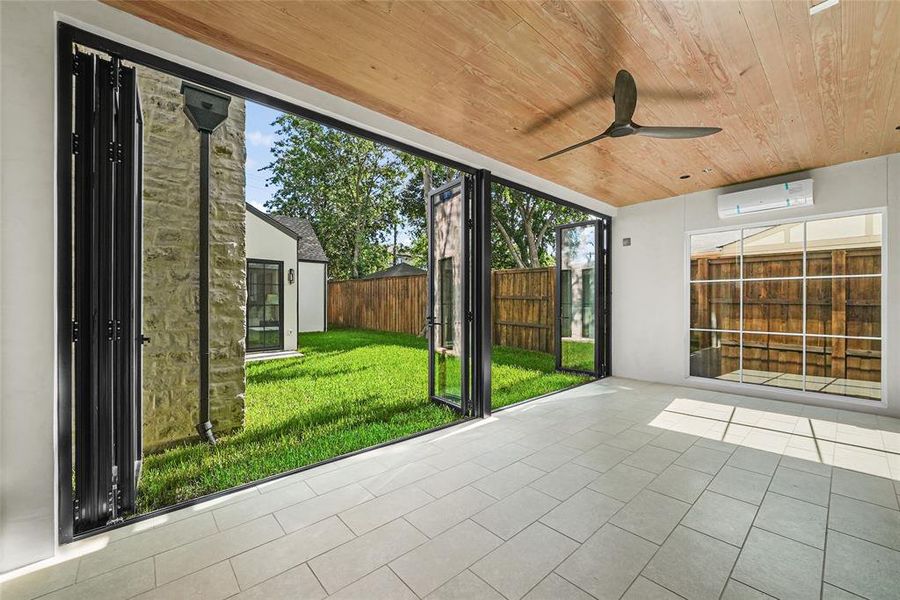 Indoor-outdoor room with large format tile flooring and a natural wood-finish ceiling