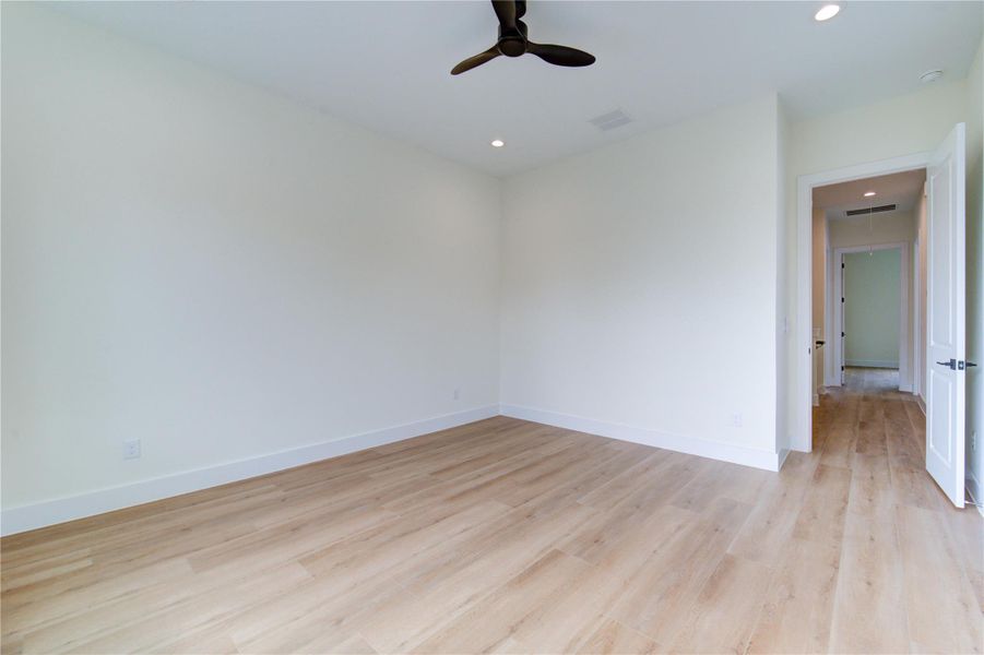 Spacious primary bedroom featuring sleek vinyl plank flooring, recessed lighting, and a modern ceiling fan for ultimate comfort. Spacious primary bedroom featuring sleek vinyl plank flooring, recessed lighting, and a modern ceiling fan for ultimate comfort.