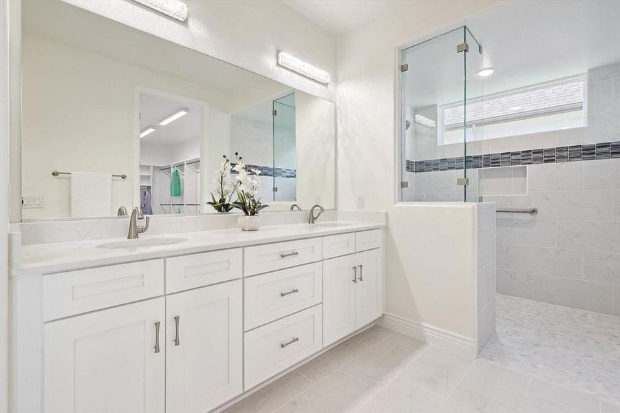 Bathroom featuring tile flooring, tiled shower, and double sink vanity