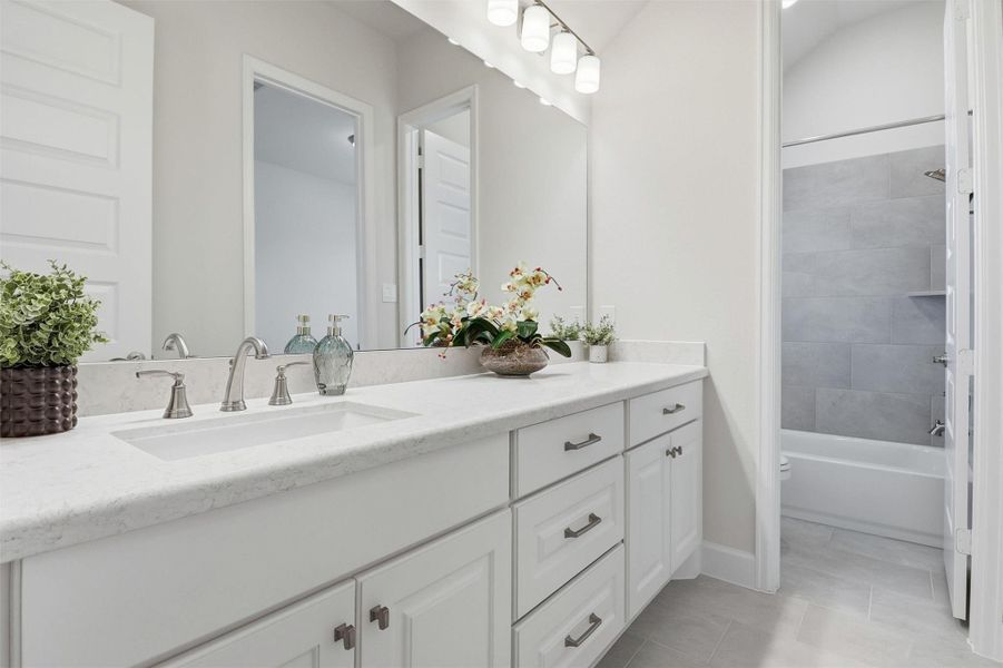 Bright white cabinets and quartz countertops. Plenty of storage space and tub/shower combo.