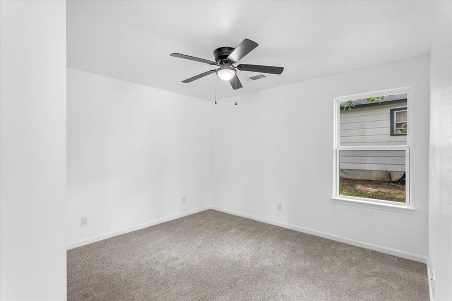 Second bedroom with ceiling fan and carpet