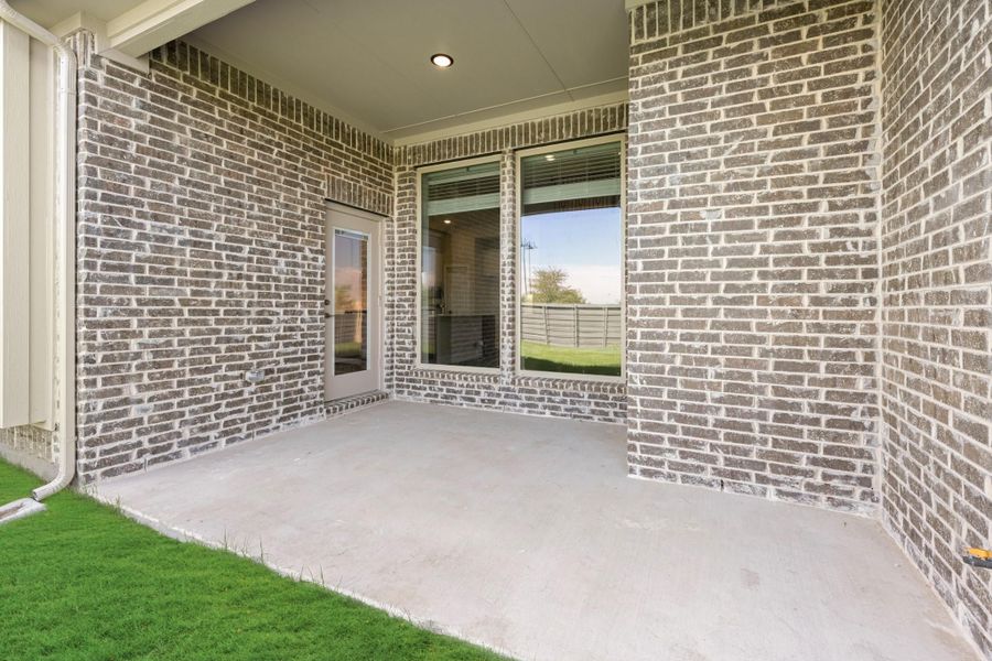Covered back patio with concrete floor, brick walls, and glass door leading inside Covered back patio with concrete floor, brick walls, and glass door leading inside
