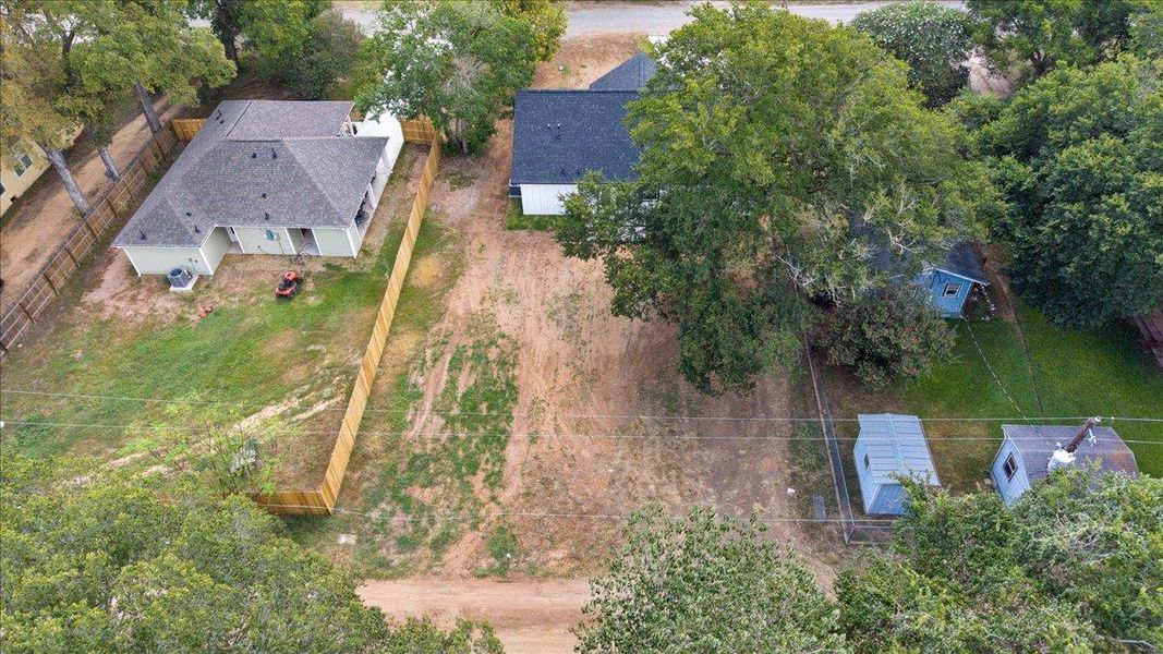 Mature trees frame a spacious residential plot with neighboring homes and outbuildings. Mature trees frame a spacious residential plot with neighboring homes and outbuildings.