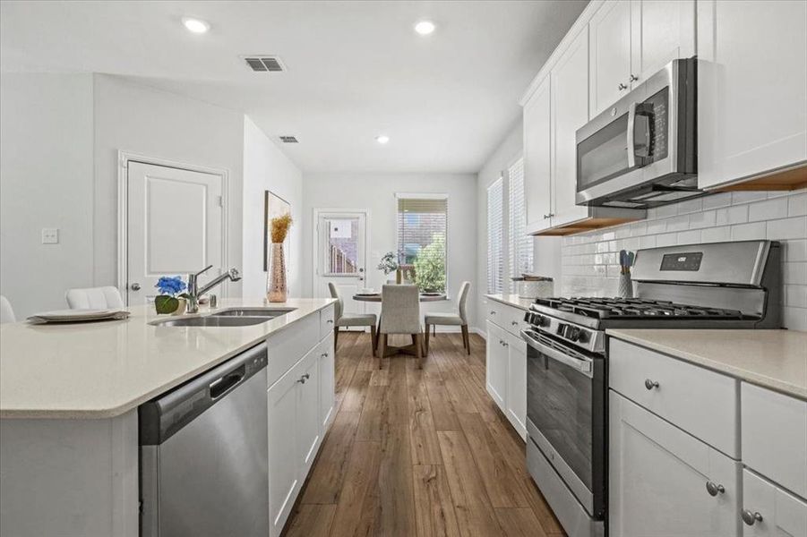 Kitchen with stainless steel appliances, white cabinetry, recessed lighting, dark wood-type flooring, and backsplash Kitchen with stainless steel appliances, white cabinetry, recessed lighting, dark wood-type flooring, and backsplash