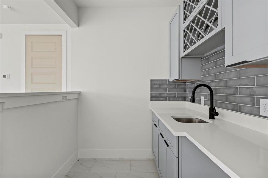 Kitchen with light marble finish floors, light countertops, and decorative backsplash Kitchen with light marble finish floors, light countertops, and decorative backsplash