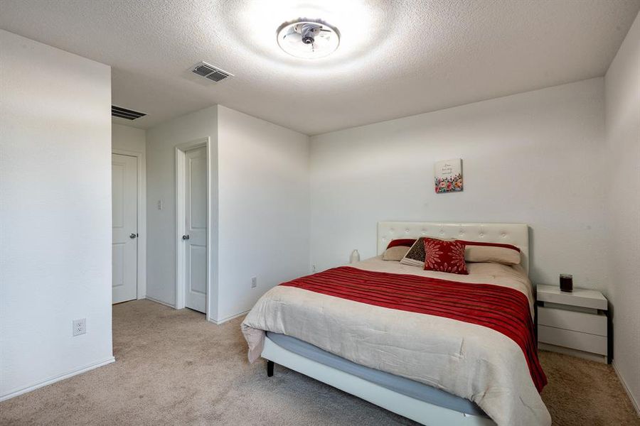 Bedroom featuring a textured ceiling and light colored carpet