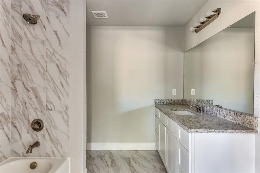 Full bath with vanity, shower / tub combination, and light marble finish flooring