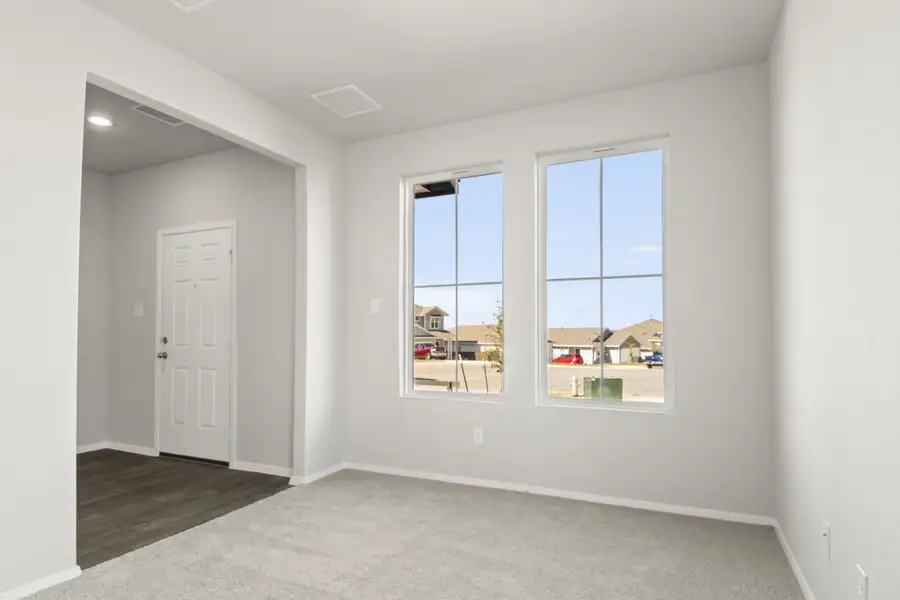 Image of an office space with tan carpeting and light grey painted walls with two windows