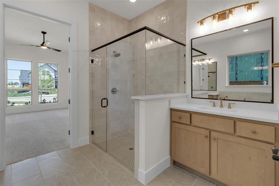 Bathroom featuring a glass-enclosed shower, single vanity with light wood cabinetry, quartz countertop, and a large framed mirror with brass-finish lighting