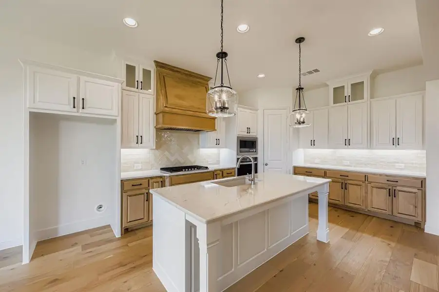 Kitchen with glass insert cabinets, white cabinetry, a kitchen bar, a kitchen island with sink, and light wood-style flooring