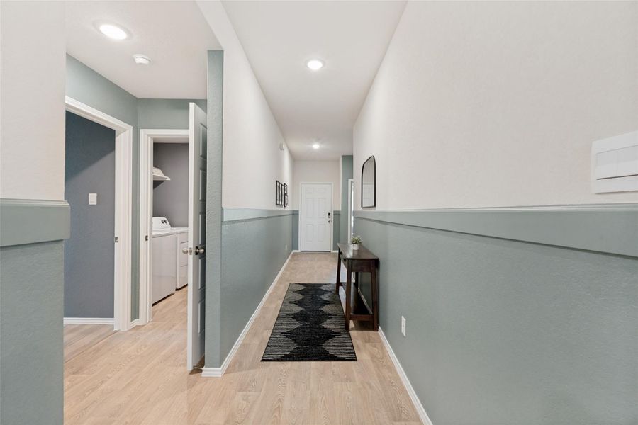 A welcoming entryway with light wood flooring extends to a utility area.