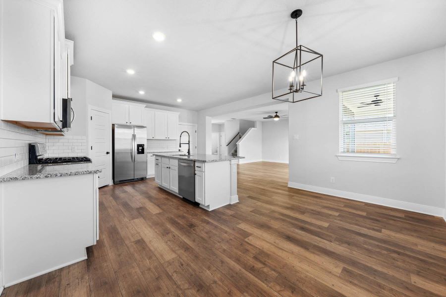 Kitchen featuring tasteful backsplash, open floor plan, decorative light fixtures, light stone countertops, and recessed lighting