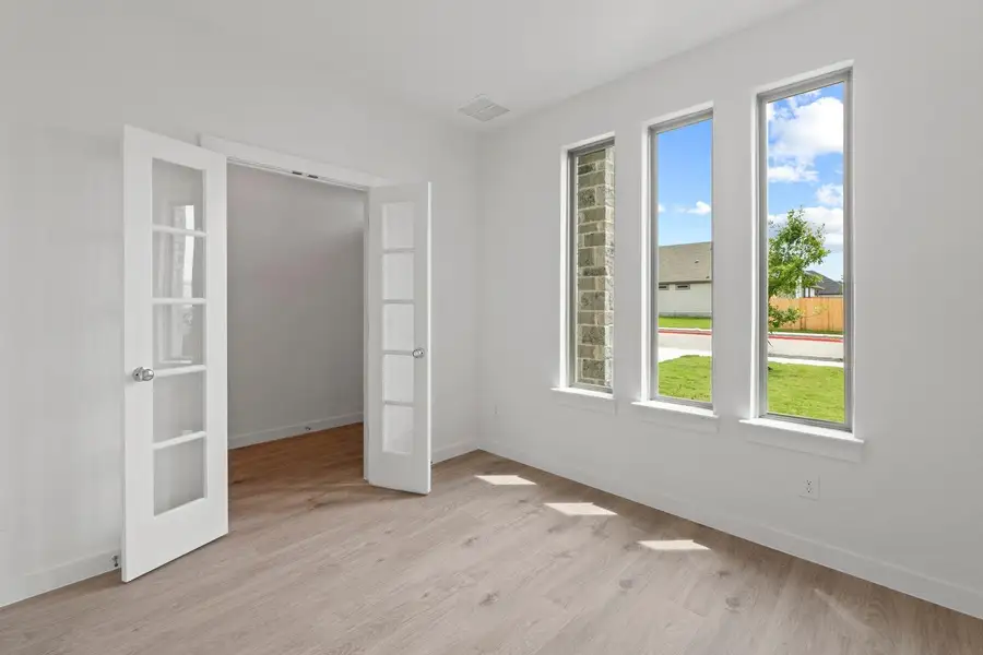 French doors open into a versatile room with abundant natural light from three tall windows. French doors open into a versatile room with abundant natural light from three tall windows.
