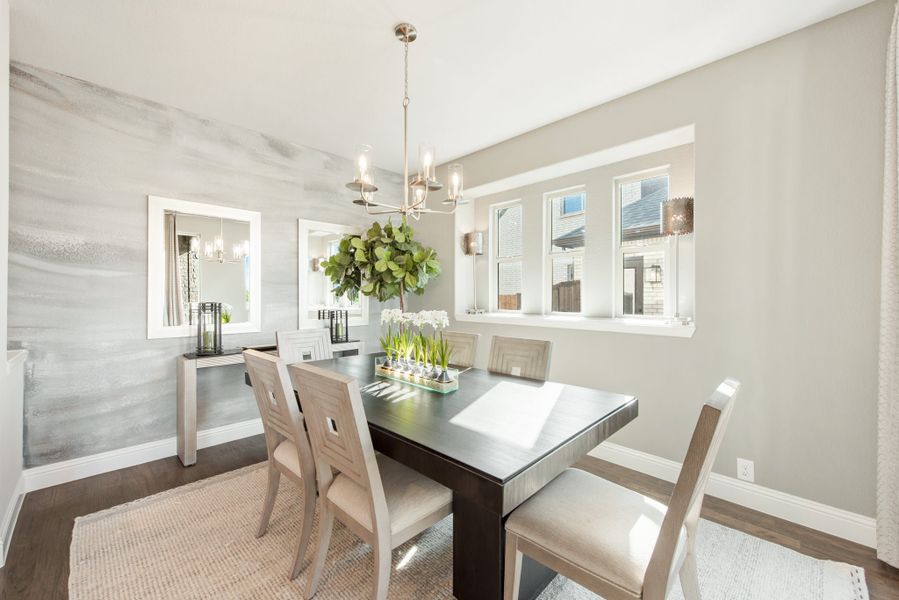 Dining room with dark wood table, neutral chairs, chandelier, and accent wall with mirrors