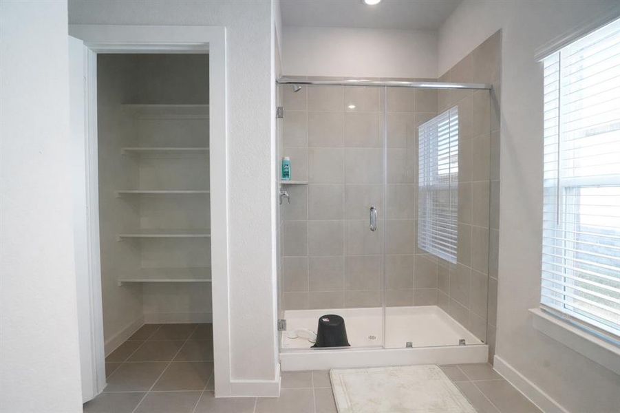 Walk-in shower with clear glass enclosure and light-toned tile surround