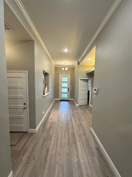 Foyer entrance featuring crown molding and wood finished floors