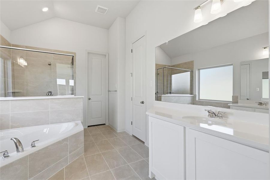 Full bathroom with lofted ceiling, vanity, a garden tub, light tile patterned floors, and a shower stall