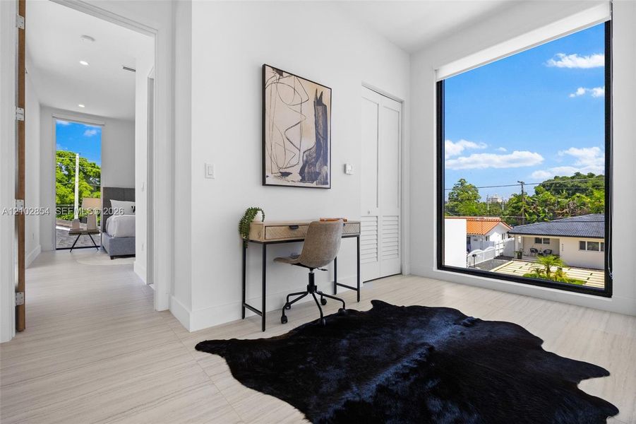 Large floor-to-ceiling windows, light-toned wood-finish flooring, and white louvered closet doors