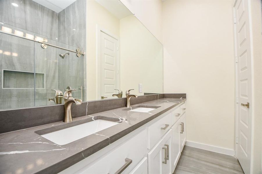 This exquisite ensuite exudes bliss with dual sinks on gleaming quartz countertop, and an oversized glass shower enclosure with porcelain tile surround. Likewise, the lush laminated floors bring an extra level of comfort into this master bath.