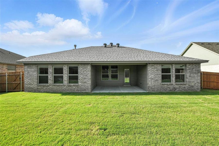 Back of house with brick siding, a fenced backyard, a patio, and roof with shingles