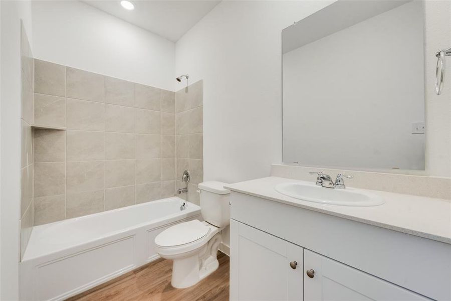 Full bathroom featuring vanity, toilet, wood-type flooring, and tiled shower / bath