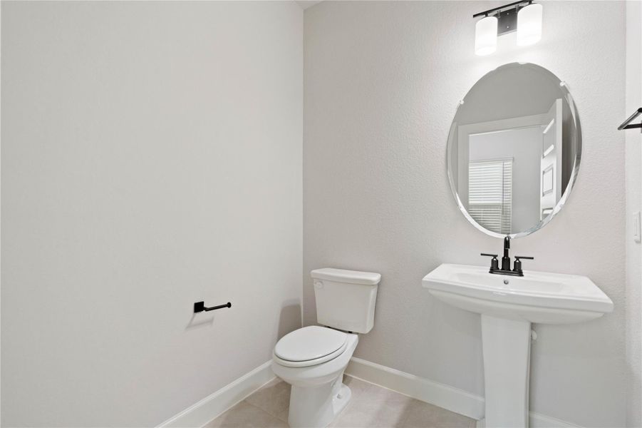 An elegant pedestal sink and oval mirror anchor this modern powder room.