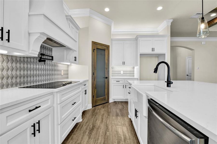 Kitchen featuring decorative backsplash, hanging light fixtures, white cabinetry, wood-type flooring, and dishwasher