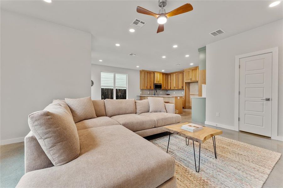 Living room featuring recessed lighting, a ceiling fan, and concrete flooring Living room featuring recessed lighting, a ceiling fan, and concrete flooring