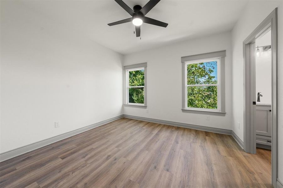 Unfurnished bedroom with connected bathroom, light wood-type flooring, and a ceiling fan