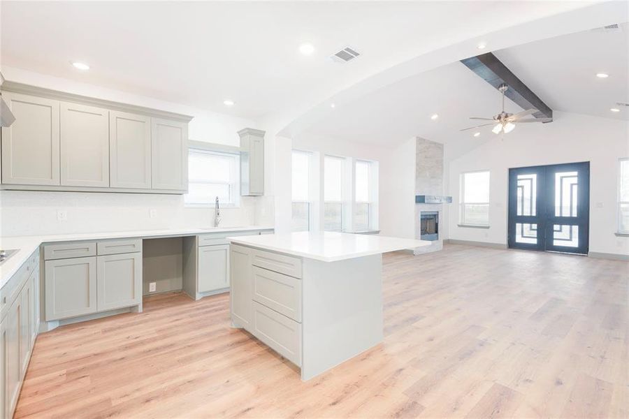 Kitchen featuring light wood-style flooring, a kitchen island, a fireplace, open floor plan, and recessed lighting