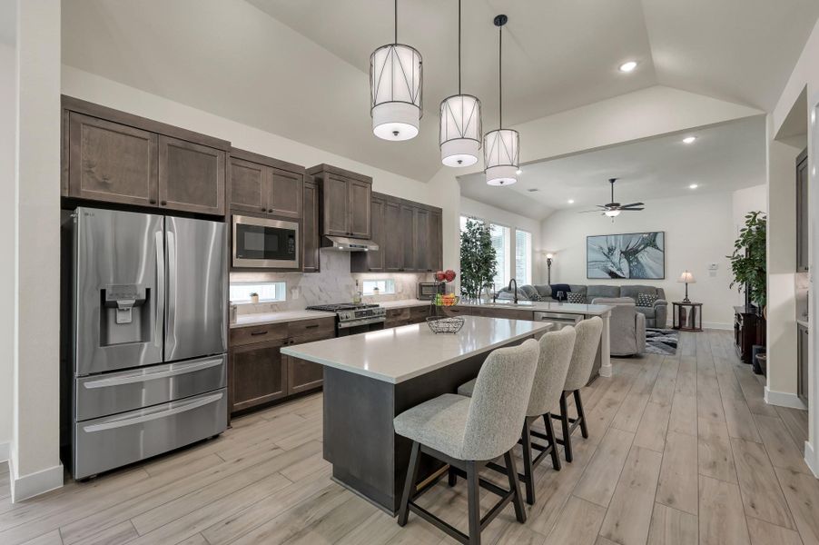 Open kitchen layout with breakfast bar seating, upgraded stainless steel appliances, a dedicated coffee bar area, and plenty of room for entertaining family and friends.
