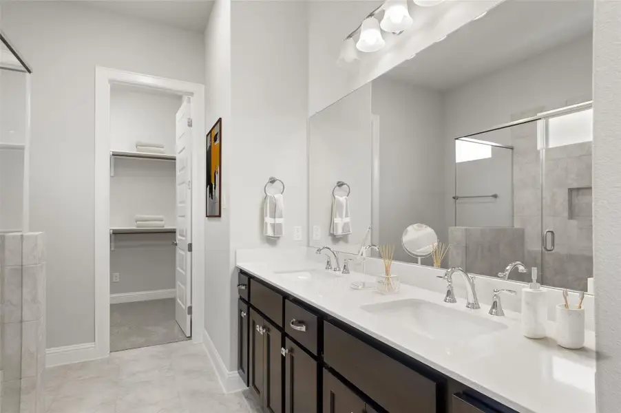 Bathroom with a walk in closet, a shower stall, and light tile patterned floors
