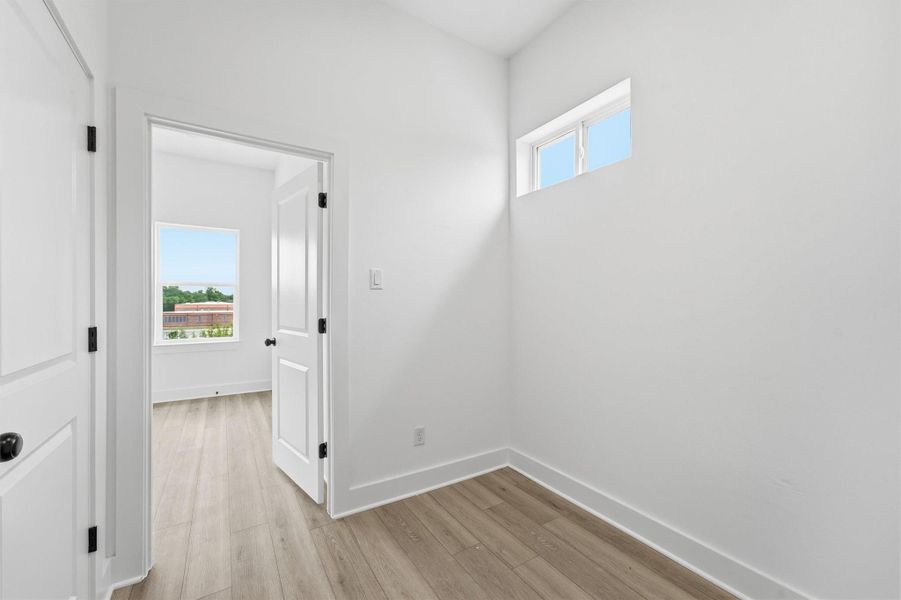 Thoughtfully designed from top to bottom. This clean upper-level landing with high ceilings, LVP flooring, and a transom window brings in natural light and connects your living spaces with the kind of flow that just feels right. Thoughtfully designed from top to bottom. This clean upper-level landing with high ceilings, LVP flooring, and a transom window brings in natural light and connects your living spaces with the kind of flow that just feels right.