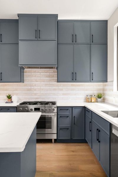 Modern kitchen features an island, hardwood floors, and sleek gray cabinetry.