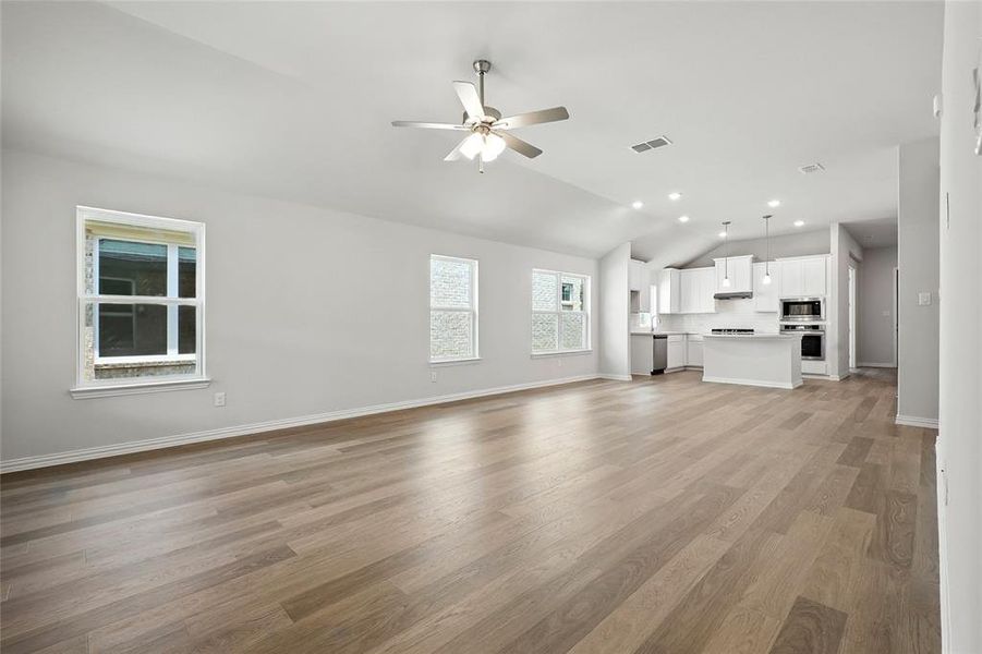 Unfurnished living room with lofted ceiling, light wood-style floors, a ceiling fan, and recessed lighting