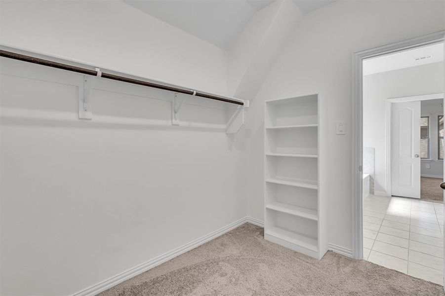 Walk in closet featuring light tile patterned flooring and vaulted ceiling