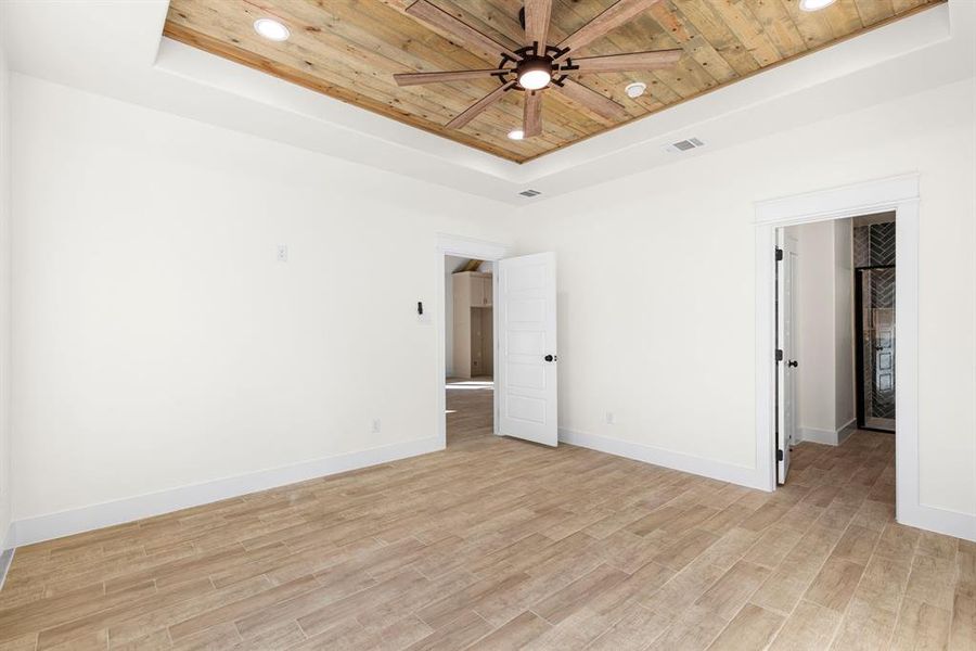 Unfurnished room featuring a raised ceiling, wood ceiling, and light hardwood / wood-style flooring