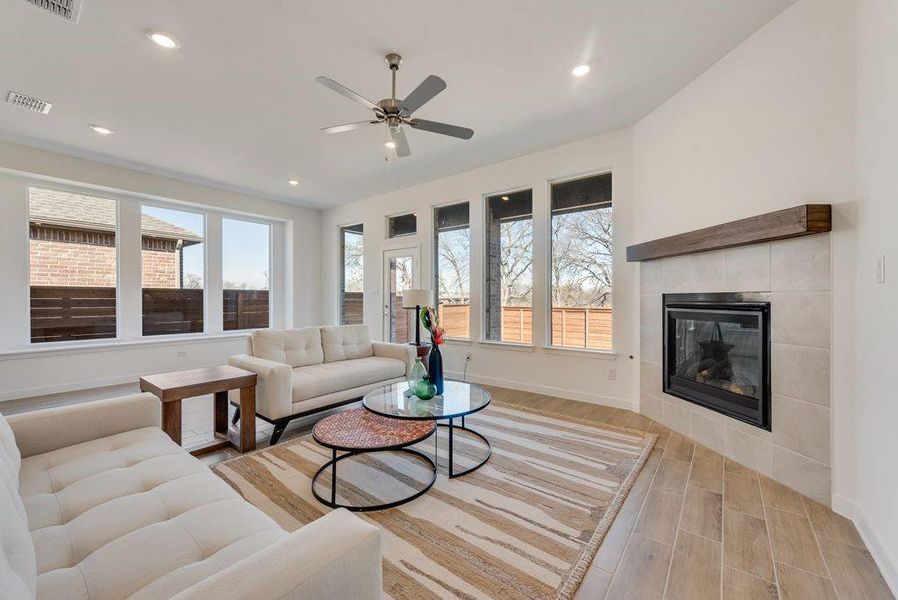 Living area featuring light wood-type flooring, a fireplace, ceiling fan, and recessed lighting