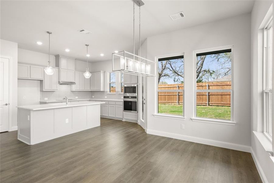 Kitchen featuring appliances with stainless steel finishes, light countertops, dark wood-type flooring, backsplash, and recessed lighting