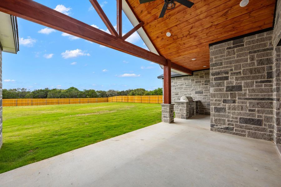 Fenced backyard with a patio area, a ceiling fan, and area for grilling