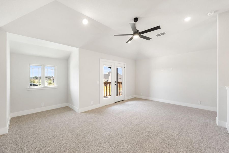 Empty room with vaulted ceiling, ceiling fan, carpet flooring, and French doors leading to a balcony