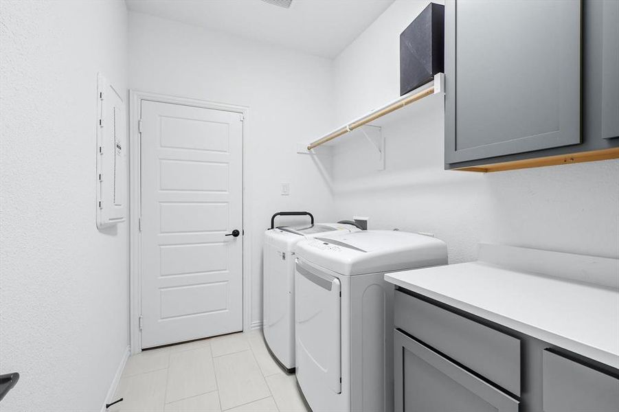Washroom with cabinet space, light tile patterned floors, independent washer and dryer, and electric panel