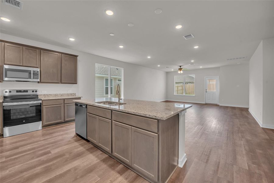 Kitchen with appliances with stainless steel finishes, recessed lighting, light stone counters, open floor plan, and light wood finished floors Kitchen with appliances with stainless steel finishes, recessed lighting, light stone counters, open floor plan, and light wood finished floors