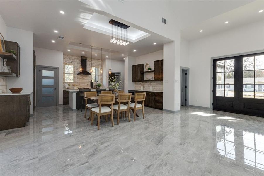 Dining space featuring a towering ceiling, french doors, and a notable chandelier